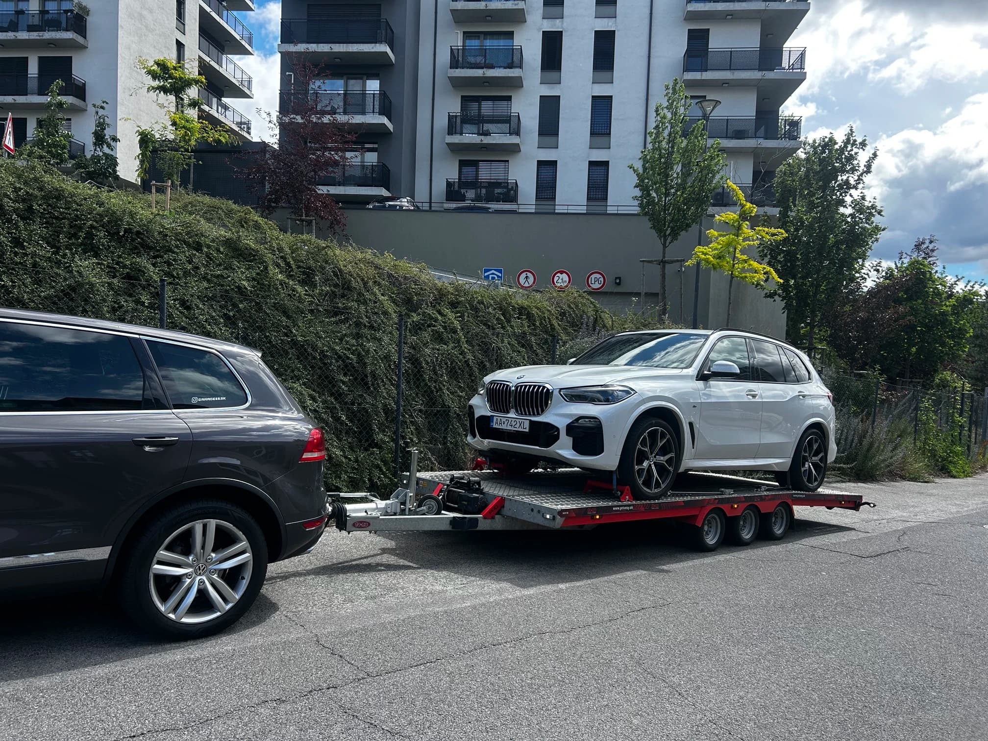 Biele BMW X5 naložené na odťahovom prívese
